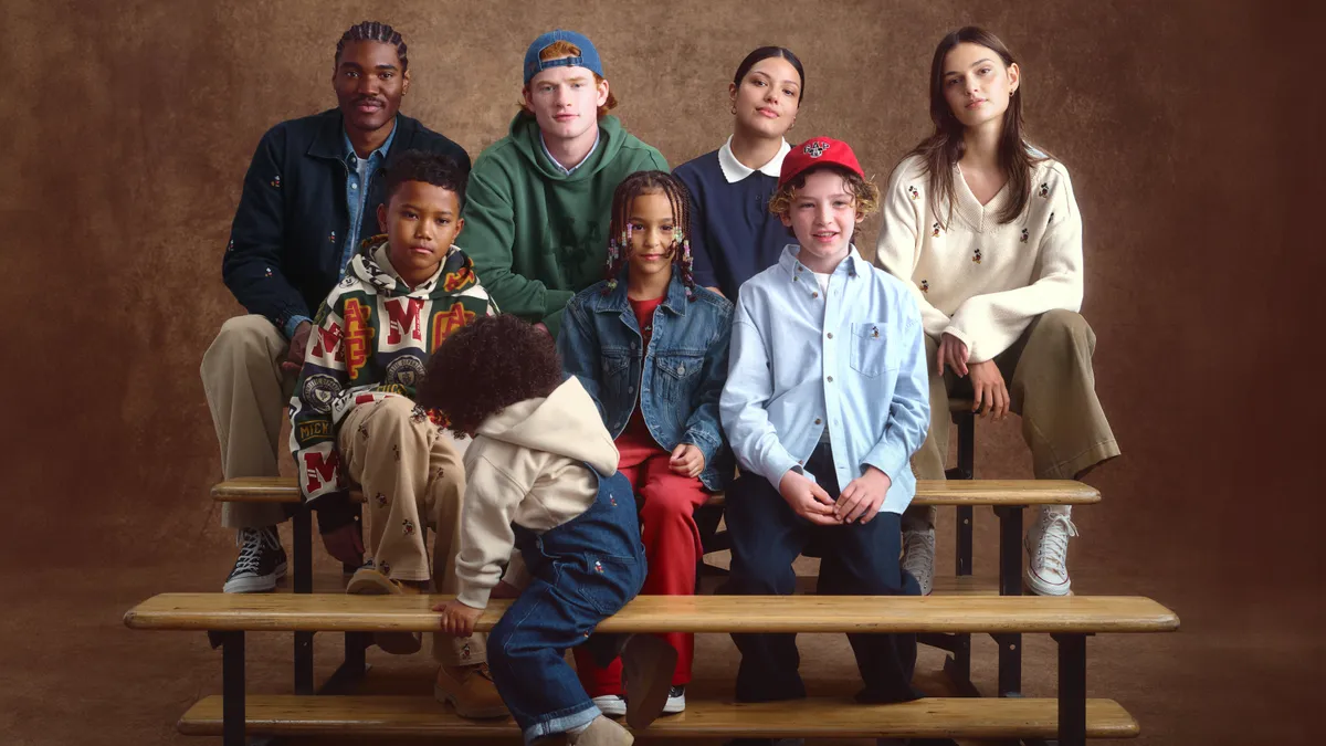 A group of people, both adults and children, sit on bleacher seats wearing casual clothing.