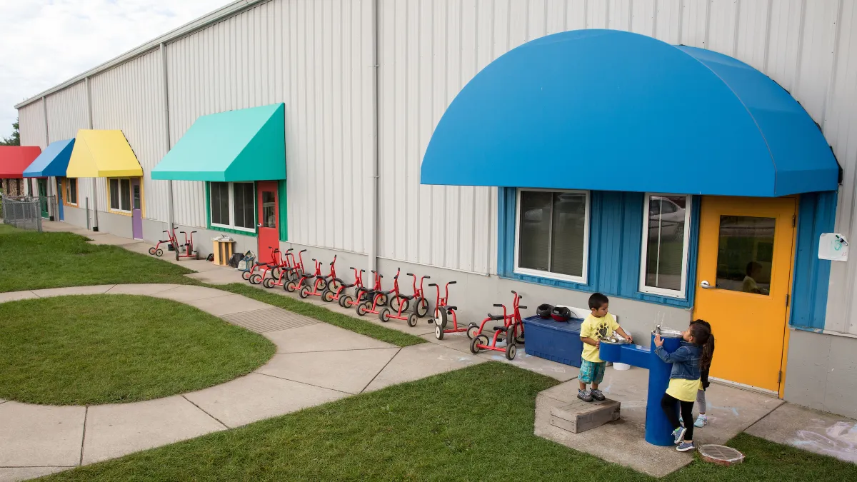 Two children are shown playing outside a Head Start early childhood learning center.