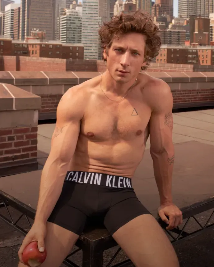 Jeremy Allen White is pictured outside on a roof top wearing black Calvin Klein underwear. He is holding an apple.