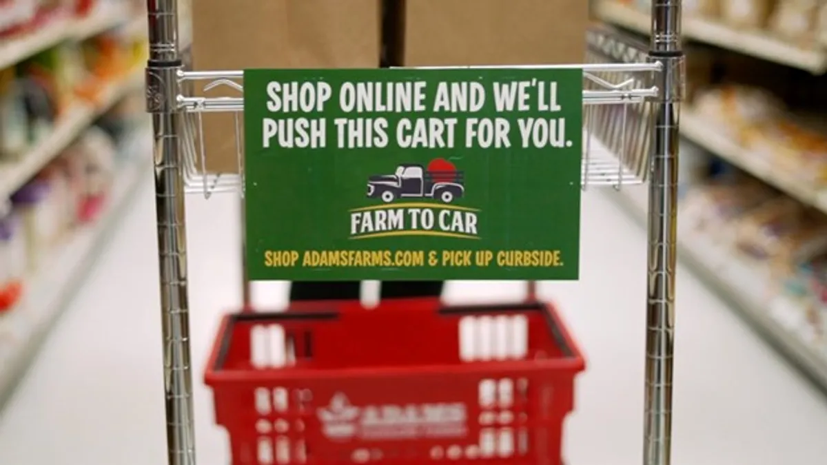 Sign on cart in grocery story that says "Shop online and we'll push this cart for you.'