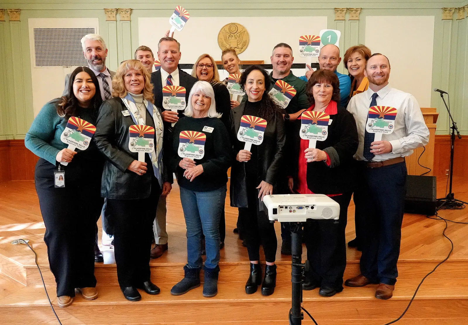 A group of people smiling facing the camera and holding auction fans