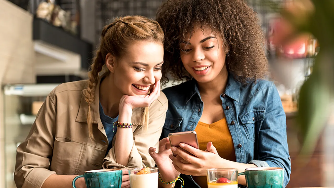 Two girls laughing at a phone screen