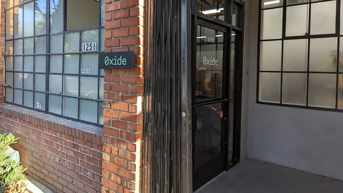 A brick building entrance is picture with a sign reading Oxide.