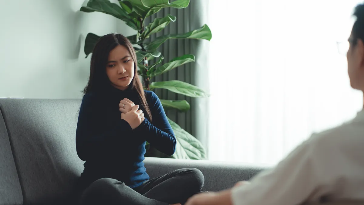 Women sitting on sofa in counseling office and talking about problems to psychologist.