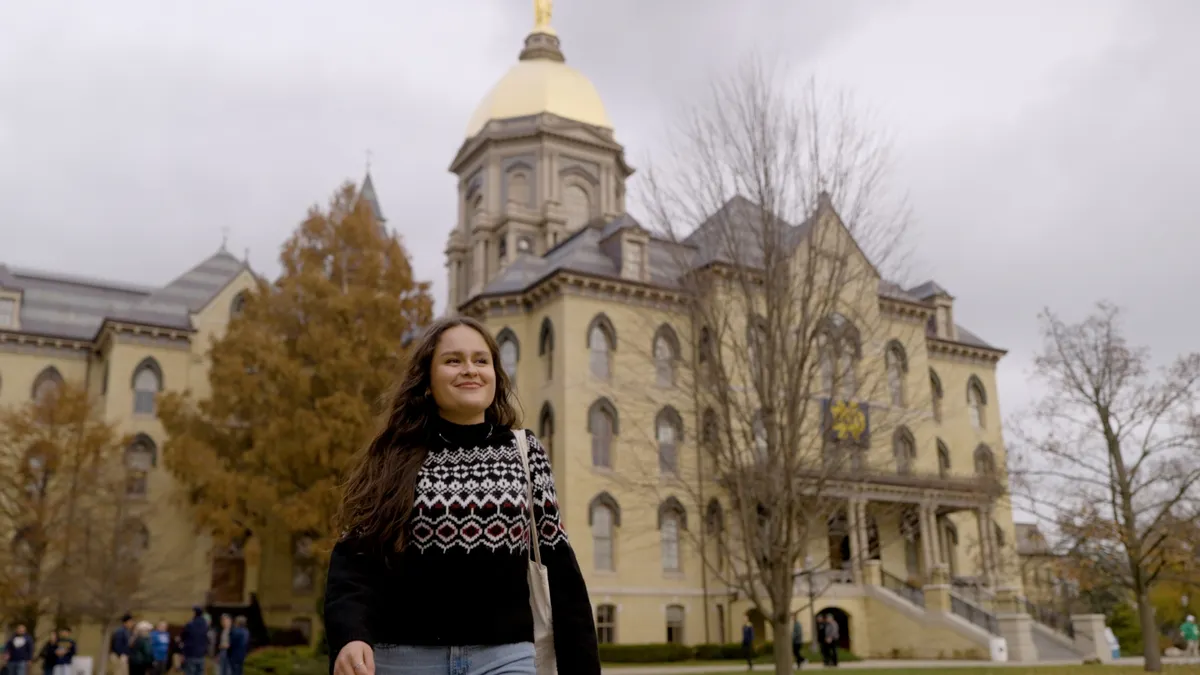 Person walking in front of a historic university building.