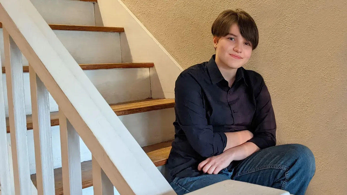 A student sits on a staircase inside a home