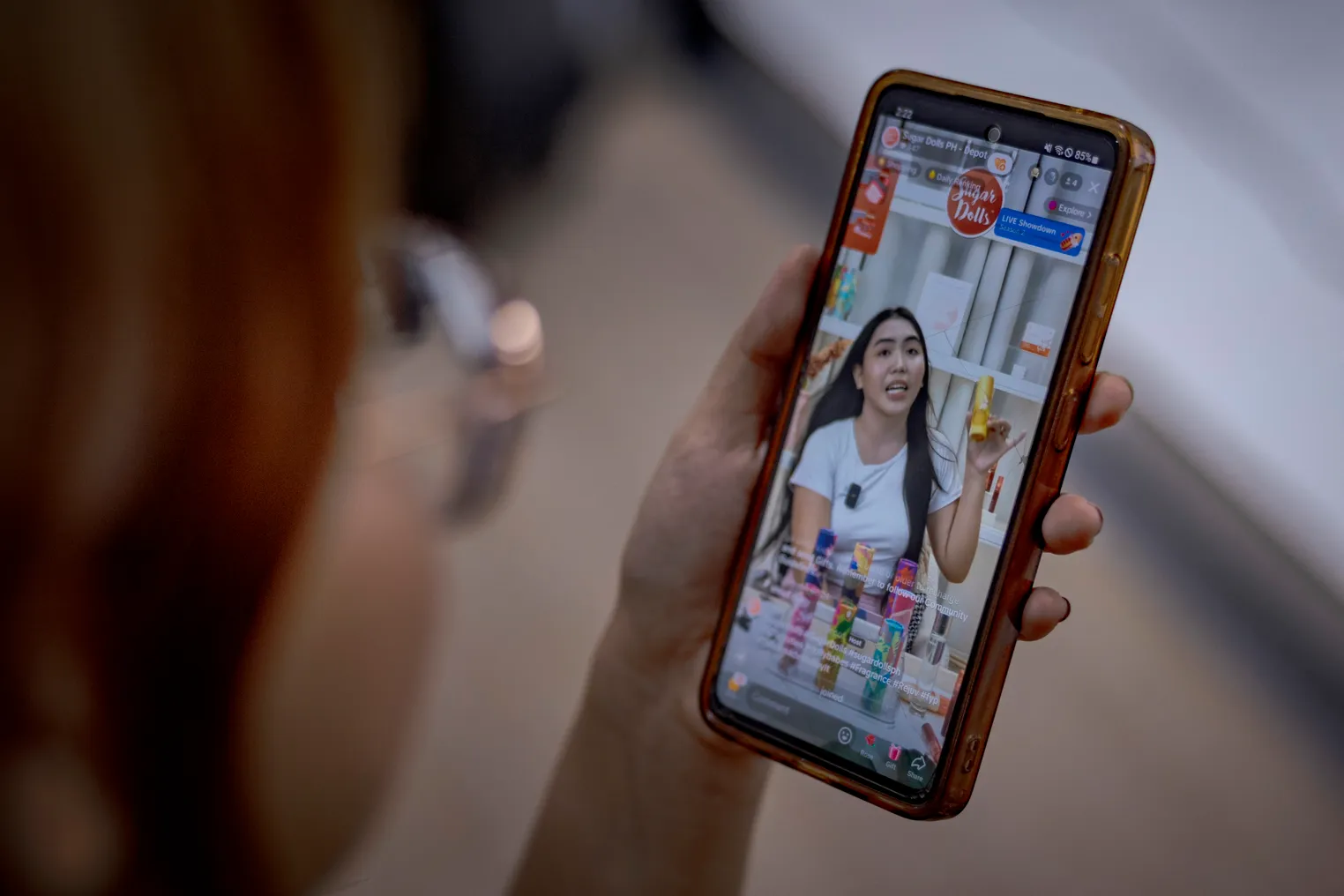 A person holds a smartphone depicting a person holding a skincare product.