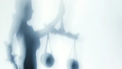 A shadow of the lady justice projected onto a white wall.