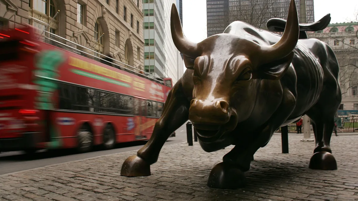 A tour bus passes the Wall Street bull.