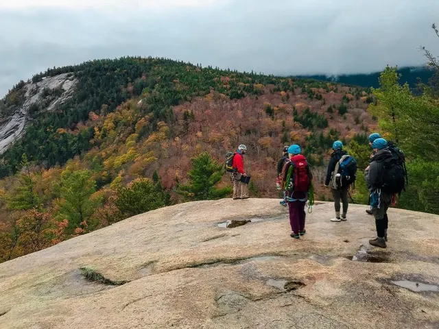 Student rock climbers standing on rocky hilltop.