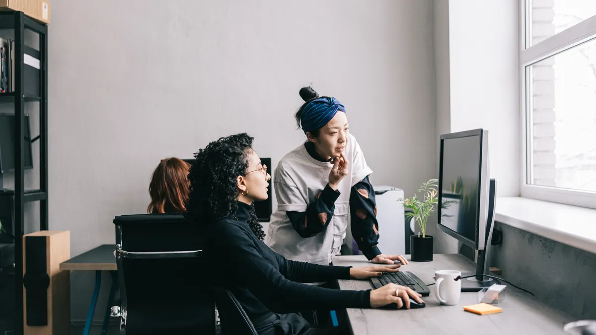 Colleagues helping each other on the computer at work