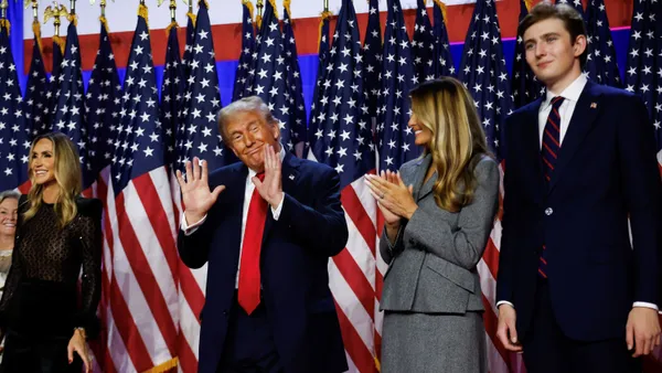 Donald Trump, center, with his hands up, facing the crowd. He's standing next to Melania and son Barron.