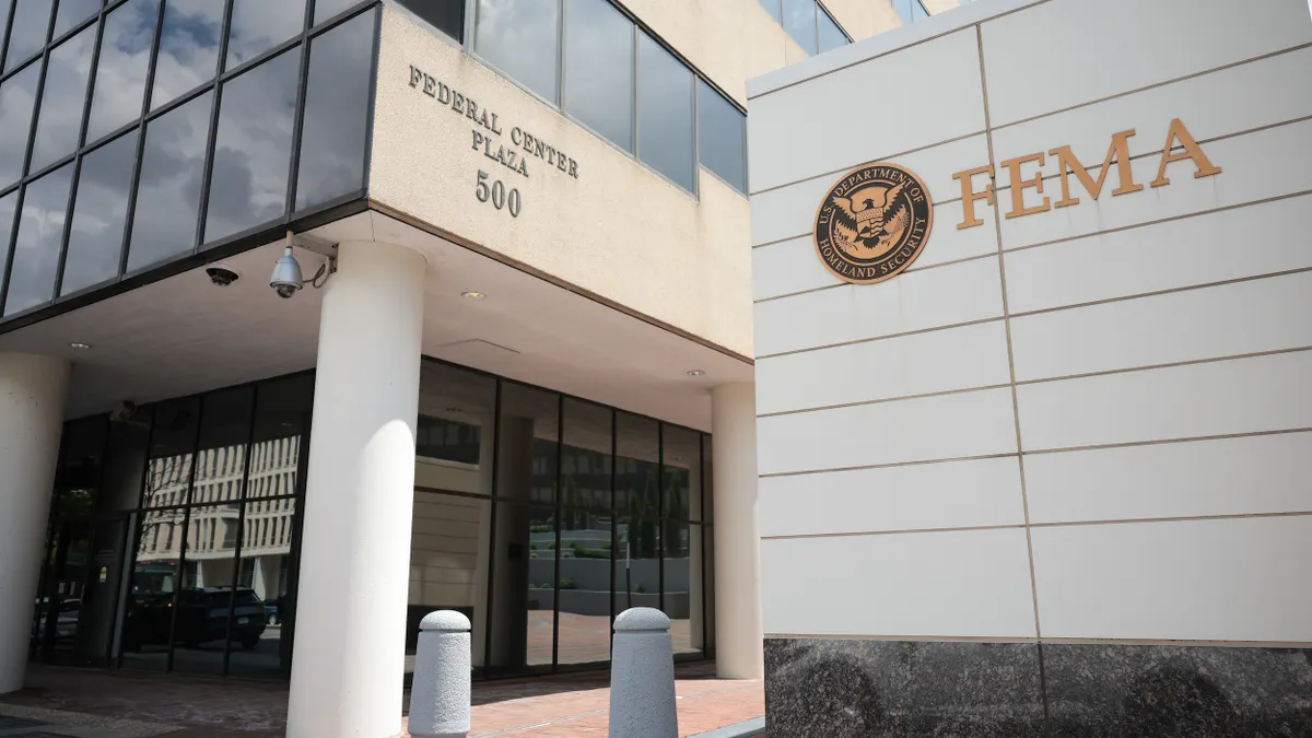 A stone and marble sign with a Department of Homeland Security seal and the letters FEMA in front of a stone building.