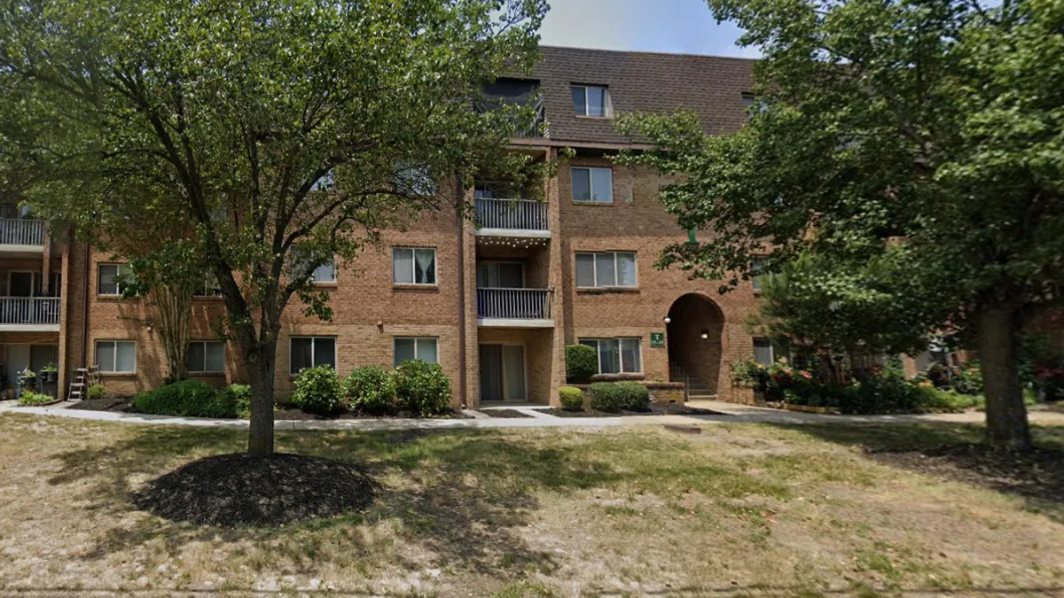 A garden-style apartment building in a wooded setting.