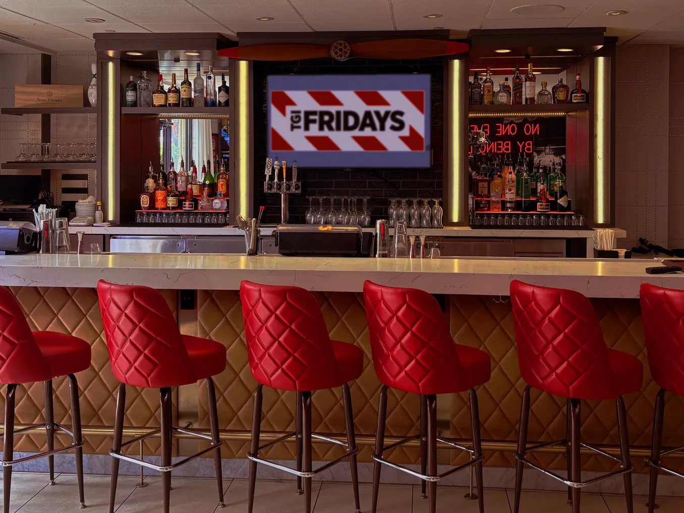 An image of a bar with red chairs and TGI Fridays signage in the background