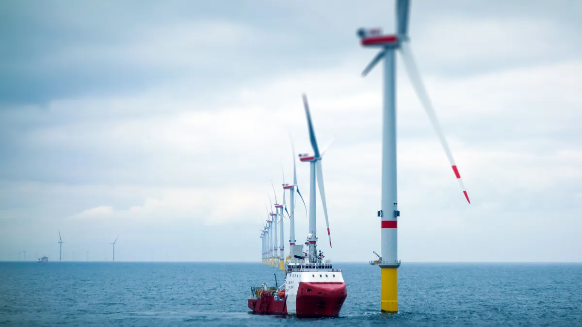 A transfer vessel bobs in the ocean near a wind turbine in an offshore wind farm.