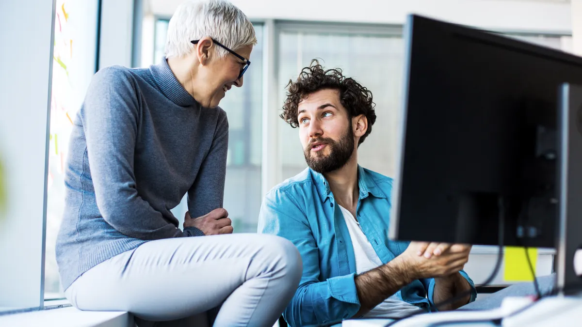 Younger colleague talks to senior business woman in the office