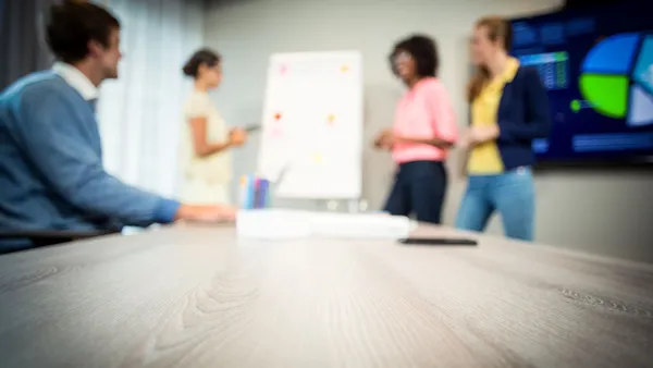 A group of people in a modern office chat over a presentation.