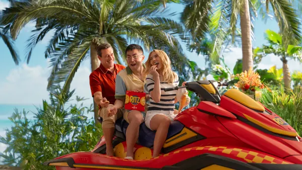 Actors Bowen Yang, Jon Hamm and Scarlett Johansson ride a jet ski against a tropical backdrop