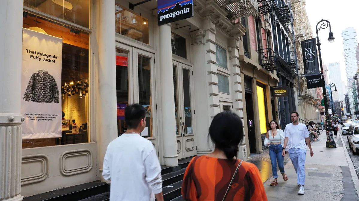 People walk past a sign for Patagonia.