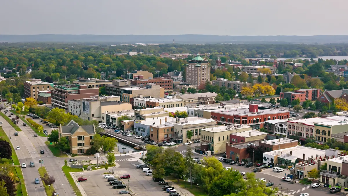Aerial view of small city surrounded by green forest.