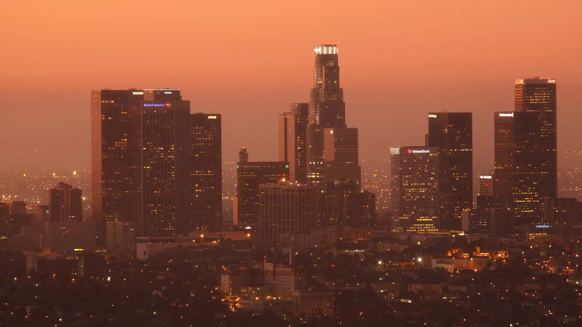 The Los Angeles skyline at night under a deep orange sky.