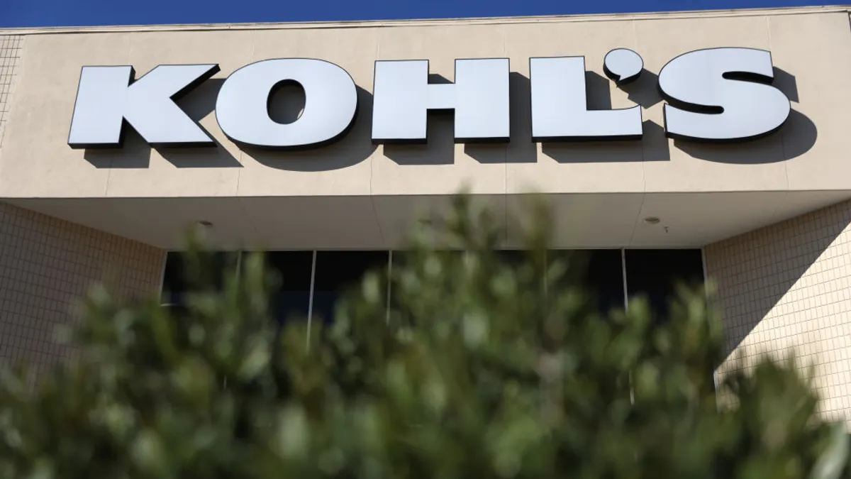 The Kohl's logo store with a view of a green bush.