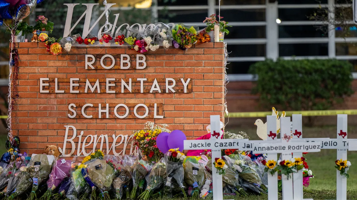 Robb Elementary School brick sign on campus adorned with flowers.