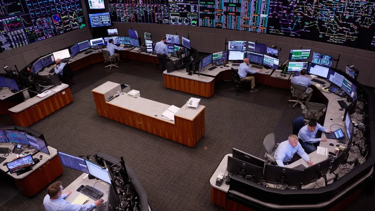 Men sit at desks with computer screens.