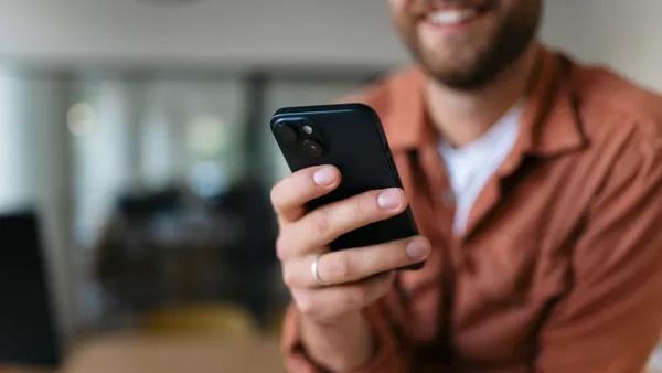 Man holding smartphone and smiling, representing communication and technology