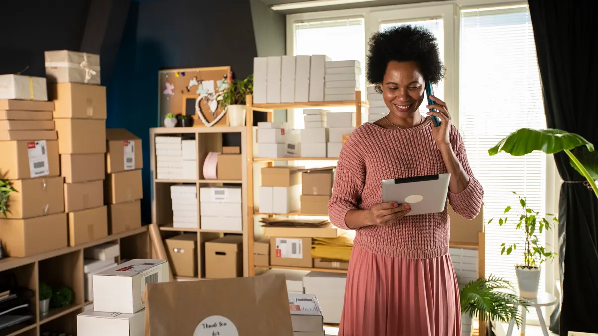 Smiling female business owner using digital tablet and talking on the phone.