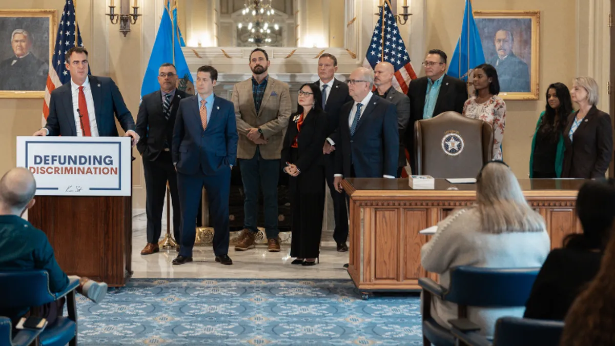 Kevin Stitt, Oklahoma governor, speaks at podium that has a sign that reads "defunding discrimination."