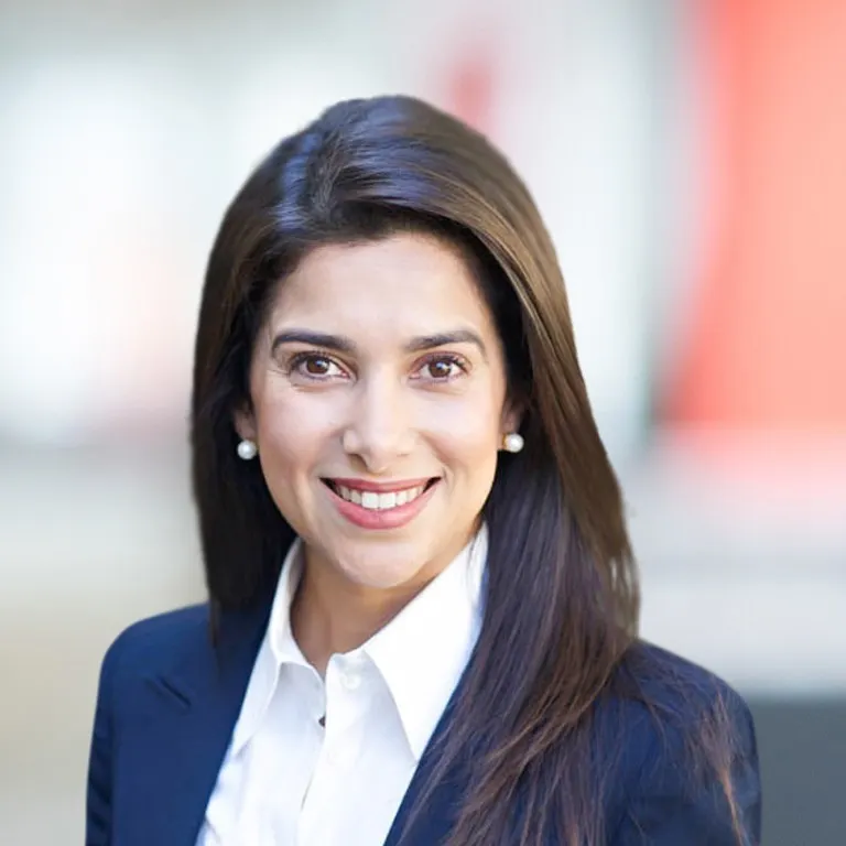 A smiling woman with dark hair in a blazer.
