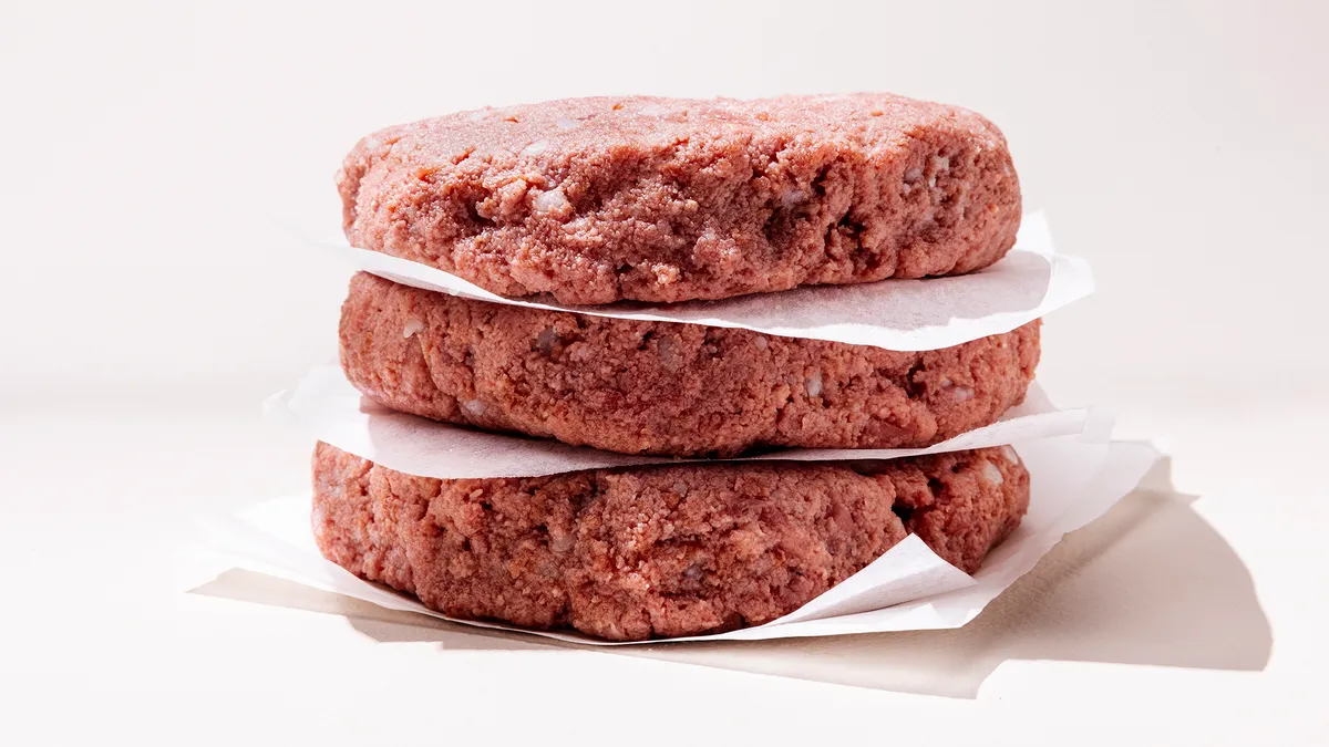 A stack of three raw burgers made from Omeat's cultivated beef.