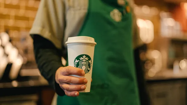 A Starbucks worker holds a beverage.