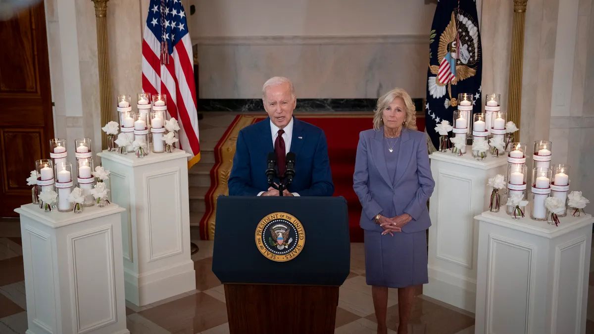 President Joe Biden and First Lady Jill Biden stand behind a podium