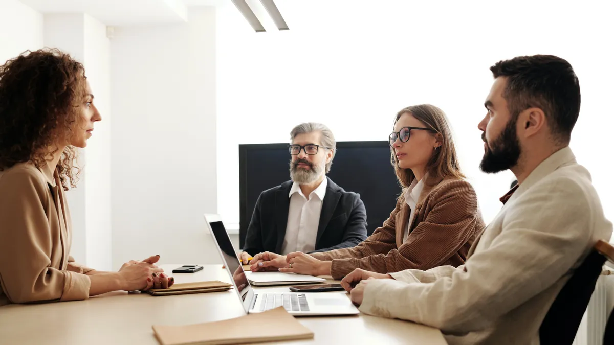 Coworkers sitting around laptop at office table