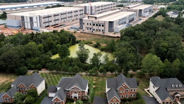 An aerial view of houses near large warehouse-looking buildings.