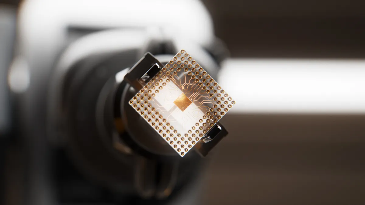 An automated robotic arm is gripping a computer chip inside of a circuit board factory.