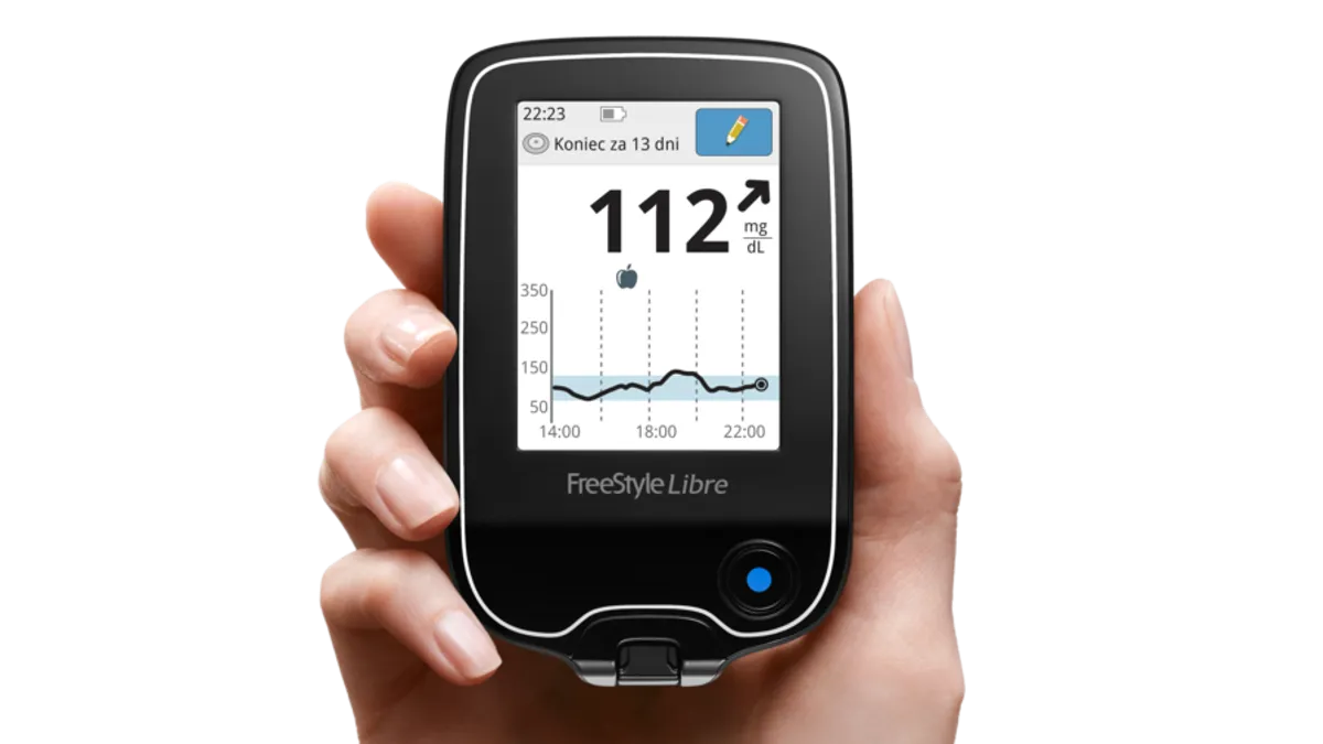 A woman's hand holds a Freestyle Libre diabetes reader