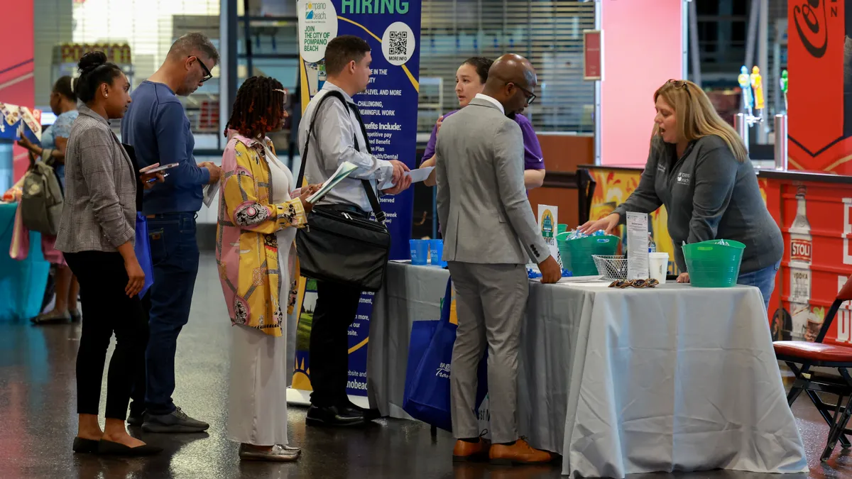 A long line of people wait to talk to a recruiter at a job fair