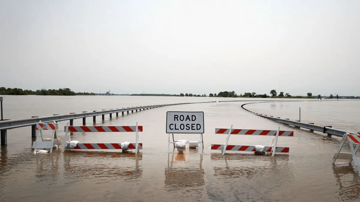 Barricade and road closed sign across road covered with floodwater from Mississippi River