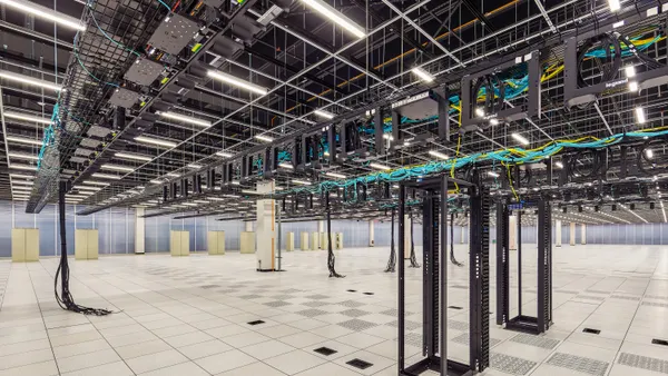 The interior of a large room with wires dangling from the ceiling in an industrial setting.
