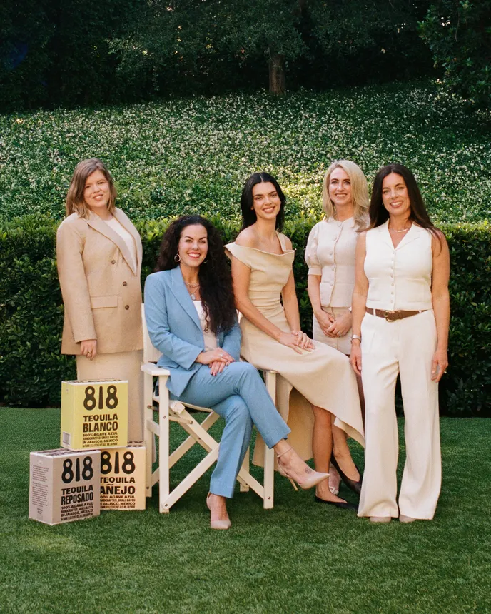 A group of women sit outdoors next to boxes of 818 Tequila.