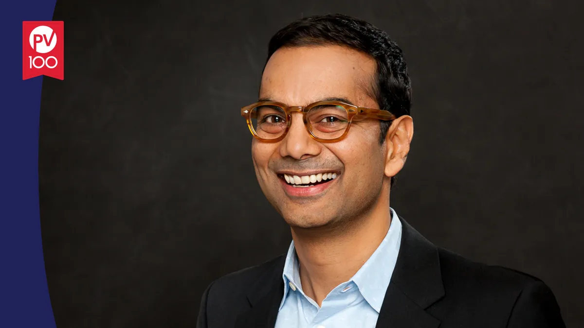 A portrait of Baba Shetty framed with a banner icon that reads "PV 100"