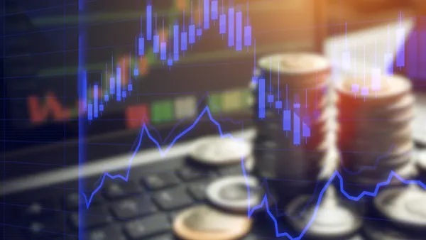 A stock market graph overlaid on a laptop and stack of coins.