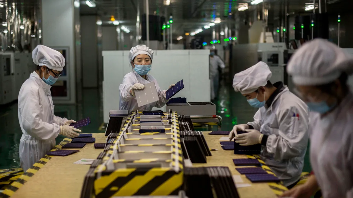 Technicians from Yingli Solar work in the final preparations of solar cells used for solar panels at the company's headquarters on December 4, 2014 in Baoding, Hebei Province.