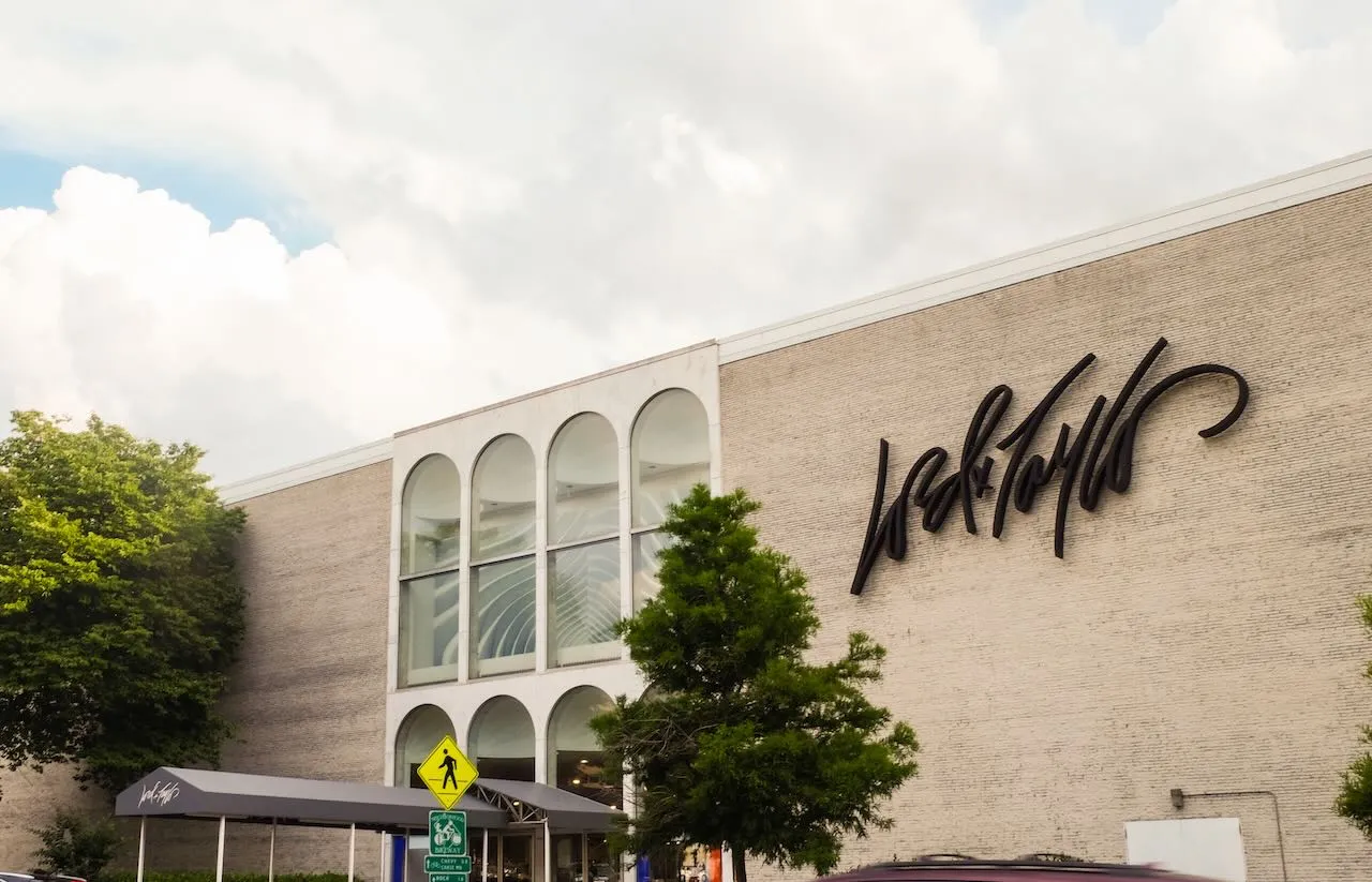 Puffy clouds and green trees frame a suburban department store building.