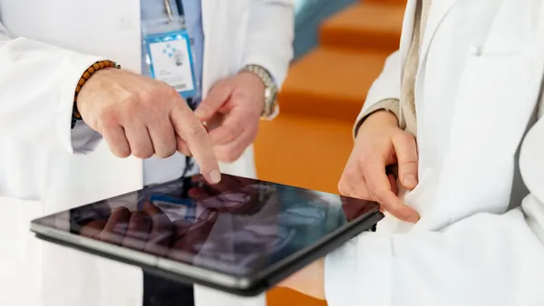 Close view of two medical professionals pointing at tablet screen during clinical review
