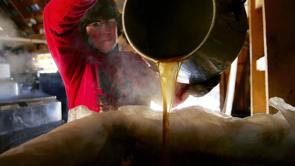 A woman is seen pouring maple syrup into a tank